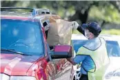  ?? JOHN RAOUX/AP PHOTOS ?? Members of Orange County Fire Rescue and volunteers pass out personal protective equipment items Wednesday in Orlando.