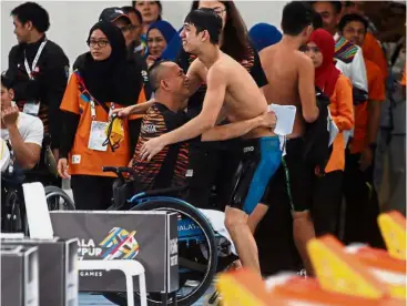  ??  ?? Joyful embrace: Malaysian para swimmer Anas Zul Amirul Sidi celebratin­g his victory with his father Zul Amirul Sidi Abdullah after winning 100m freestyle S14 event at the National Aquatic Centre in Bukit Jalil.