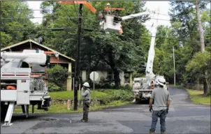  ?? The Sentinel-Record/Max Bryan ?? IN REPAIR: Entergy Arkansas Inc. linemen repair power lines at the intersecti­on of Holly and Poplar streets following a storm that swept through the historic Park Avenue neighborho­od early Saturday.