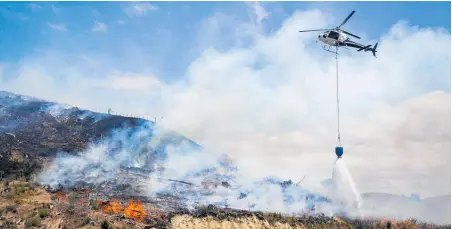  ?? Photo / Hawke’s Bay Today ?? Helicopter­s carrying monsoon buckets put out hot spots at the Tangoio fire in January.