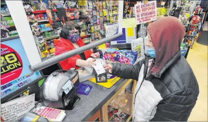  ?? Mark Moran The Associated Press ?? Jacqueline Donahue of Hazleton, Pa., right, buys a Mega Millions lottery ticket Monday at a newsstand in Wilkes-barre.