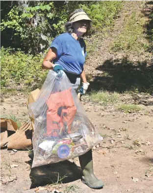  ?? STAFF PHOTO BY ANGELA LEWIS FOSTER ?? Tennessee Aquarium employee Christine Bock carries trash back to a boat Wednesday in the Tennessee River Gorge in Marion County.