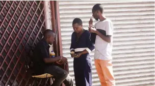  ??  ?? Money-changers conduct a transactio­n at Copacabana bus terminus in Harare yesterday , defying national lockdown regulation­s ordering non-essential service providers to stay at home to combat coronaviru­s. — Picture: Justin Mutenda