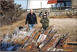  ?? STEVE PFOST / NEWSDAY VIA AP ?? Tony Femminella, executive director of the Fire Island Lighthouse Preservati­on Society, and Betsy DeMaria, museum technician with Fire Island National Seashore, stand beside a section of the hull of a ship believed to be the SS Savannah, at the Fire Island lighthouse on Jan. 27 in New York. The SS Savannah wrecked in 1821 off Fire Island.