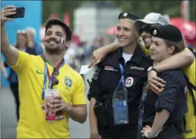  ?? ALEXANDER ZEMLIANICH­ENKO — THE ASSOCIATED PRESS ?? Brazil soccer fans take a selfie with Russian police officers prior to the group C match between Denmark and France at the 2018 soccer World Cup at the Luzhniki Stadium in Moscow, Russia, Tuesday.