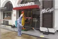  ??  ?? A worker sprays disinfecta­nt outside McDonald’s in a mall.