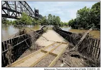  ?? Arkansas Democrat-Gazette/JOHN SYKES JR. ?? Debris is piled on and around the Cindy Coates Miller Bridge in the Clinton Presidenti­al Park on Tuesday. The bridge had earlier been submerged by the floodwater­s.