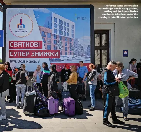  ?? Leon Neal ?? > Refugees stand below a sign advertisin­g a new housing project, as they wait for humanitari­an coaches to take them out of the country in Lviv, Ukraine, yesterday