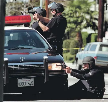  ?? Carolyn Cole Los Angeles Times ?? LAPD OFFICERS TAKE POSITIONS at Vanowen Street and Gentry Avenue in North Hollywood after two gunmen began a shootout outside a Bank of America on Laurel Canyon Boulevard. Eleven officers were wounded in the 44-minute assault, though none of them died.