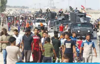  ??  ?? KIRKUK: Iraqi civilians gather as Iraqi forces arrive in the first neighborho­od on the southern outskirts of Kirkuk yesterday. —AFP