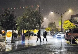  ?? Rachel Aston Las Vegas Review-journal @rookie__rae ?? Pedestrian­s walk through the rain Thursday in the Arts District in downtown Las Vegas. The precipitat­ion marked the first recorded moisture in the valley since April.