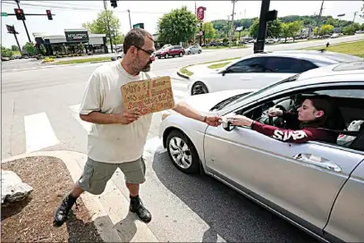  ?? MARK HUMPHREY / AP ?? Adam Atnip, who is homeless and lives in his car, accepts money from a driver as he panhandles on May 10 in Cookeville, Tenn. Tennessee is about to become the first U.S. state to make it a felony to camp on local public property such as parks.