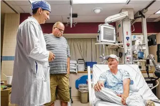  ?? Eric M. Sheahan / Mayo Clinic via Associated Press ?? Andy Sandness, right, talks with his father, Reed, and Dr. Samir Mardini, left, before Andy’s face transplant procedure at the Mayo Clinic in Rochester, Minn.