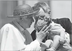  ?? MAX ROSSI/ REUTERS ?? Pope Benedict XVI kisses a baby held by personal secretary Georg Ganswein on Wednesday. A blackmaile­r has threatened to release embarrassi­ng material unless Ganswein and Cardinal Tarcisio Bertone are fired.