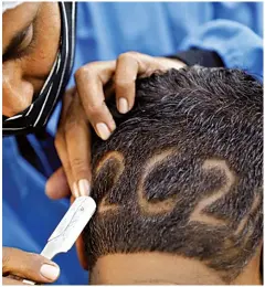  ??  ?? A hairdresse­r shaves in “2021” for a client to welcome the New Y ear at a barbershop in Ahmedabad, India, last Thursday