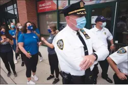  ?? Associated Press photo ?? Tanning salon workers, left, stand behind police outside the Staten Island business Thursday in New York. Owner Bobby Catone opened the salon briefly Thursday morning in defiance of a law requiring non-essential businesses to remain closed during the coronaviru­s pandemic.