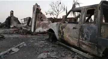  ??  ?? The charred remains of a destroyed vehicle and home stand in the aftermath of the Holiday Fire in Goleta, California. — AFP photo