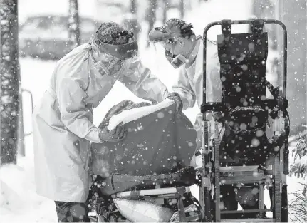  ?? ALLEN MCINNIS • POSTMEDIA FILES ?? Paramedics fight with snow and cold as they load an elderly COVID-19 suspect case into an ambulance in Montreal, on Jan. 16, 2021.