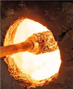  ??  ?? Will inserts the end of the metal iron, or rod, into the fierce heat of the furnace to pick up molten soda glass (top and bottom left). He then rolls it in the shards scattered on a metal marver before using a smaller, but even hotter, furnace to melt the colour into the bauble (top and bottom right).