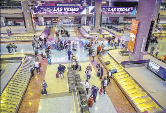  ?? L.E. Baskow Las Vegas Review-Journal @Left_Eye_Images ?? People retrieve their baggage at Terminal 1 as holiday travel at McCarran Internatio­nal Airport continues Thursday.