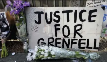  ?? KIRSTY WIGGLESWOR­TH — THE ASSOCIATED PRESS ?? A poster and flowers are left near Grenfell Tower in London, Saturday. Police Commander Stuart Cundy said Saturday it will take weeks or longer to recover and identify all the dead in the public housing block that was devastated by a fire early...