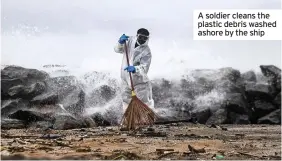  ??  ?? A soldier cleans the plastic debris washed ashore by the ship