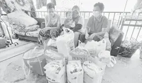  ?? — Gambar Bernama ?? HILANG PUNCA: Julia (tengah) dan suaminya, Mohamad Syamrezlan (kanan) bersama barang sumbangan selepas menerima bantuan di rumahnya di Kampung Tengku Hussein, Manjoi dekat Ipoh, semalam.