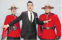  ??  PETER POWER/THE CANADIAN PRESS ?? Host Jacob Hoggard of Hedley hams it up with some Mounties on the Juno Awards red carpet.