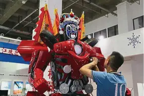  ??  ?? Sophistica­ted machines: An exhibitor is seen here adjusting a robot on display at the World Robot Conference in Beijing. - China Daily