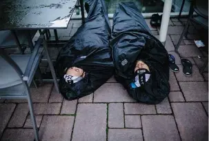  ??  ?? Below: Two riders try to get some sleep before the 10pm start in Geraardsbe­rgen, Belgium