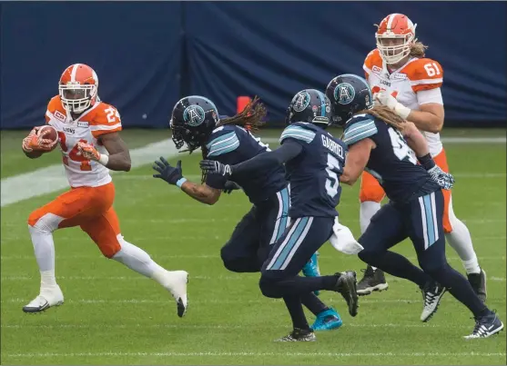  ?? CHRIS YOUNG/The Canadian Press ?? BC Lions running back Jeremiah Johnson, left, takes the ball away from Toronto Argonauts defenders in Toronto on Friday.