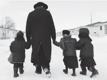  ?? DAVE CHIDLEY/ THE CANADIAN PRESS ?? Members of the Lev Tahor sect walk down a street in Chatham, Ont. There are 127 children in the community.