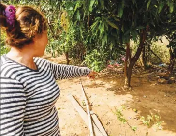  ?? ELIAH LILLIS ?? Nou Pharny points to where she found an intact skeleton wearing the Khmer Rouge’s signature red krama.