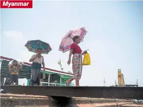  ?? — AFP ?? Shielding from the sun: Women walking around with umbrellas to shelter from the sun on a hot day in Yangon.
