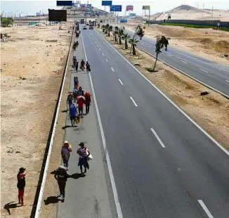  ?? Sebastian Castaneda - 21.abr.20/Reuters ?? Peruanos caminham para tentar tomar ônibus para deixar Lima