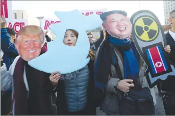  ?? AP PHOTO ?? Anti-war protesters wearing cutouts of U.S. President Donald Trump and North Korean leader Kim Jong Un march near the U.S. Embassy in Seoul, South Korea, after a rally demanding peace on the Korean peninsula.