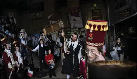  ?? ODED BALILTY — THE ASSOCIATED PRESS ?? Jewish ultra-orthodox men and children, some wearing costumes, celebrate the festival of Purim at a synagogue in Bnei Brak, Israel, in 2022. Purim celebrates the biblical story of how a plot to exterminat­e Jews in Persia was thwarted.