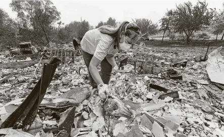  ?? Jose Carlos Fajardo / Associated Press ?? Sarah Hawkins finds a vase in the rubble Thursday after her Vacaville, Calif., home was destroyed by a fire. The LNU Complex fires have killed at least six people and destroyed more than 500 structures as they have spread across 780 square miles.