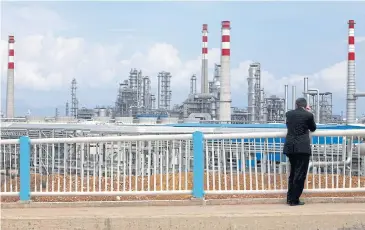  ??  ?? File photo shows a visitor looking at state-owned CNOOC’s oil refinery in Huizhou, Guangdong province.