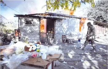  ?? — AFP photos ?? In this file photo taken on Nov 14, 2020 shows a man walks past as a house burns in the village of Charektar outside the town of Kalbajar, during the military conflict between Armenia and Azerbaijan.