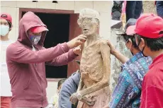  ?? CAITLIN DOUGHTY. ?? Family members clean the mummified body of a relative in Indonesia.