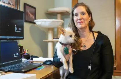  ?? ?? Dr. Amanda Schnitker, hospital director of Uptown Animal Hospital and Companion River North, sits with her dog in her home office Tuesday. She said her hospitals saw two cases last month that were likely related to the mystery illness.