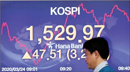  ??  ?? A currency trader walks by a screen showing the Korea Composite Stock Price Index (KOSPI) at the foreign exchange dealing room in Seoul, South Korea on March 24, 2020. Asian stock markets gained Tuesday after the US Federal Reserve promised support to the struggling economy as Congress
delayed action on a $2 trillion coronaviru­s aid package. (AP)