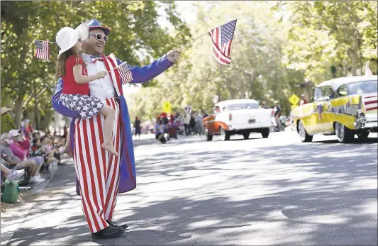  ?? JOSIE LEPE — STAFF ARCHIVES ?? David Manzo holds daughter Twyla as they wave flags while watching the annual Rose, White & Blue Parade in San Jose last year.