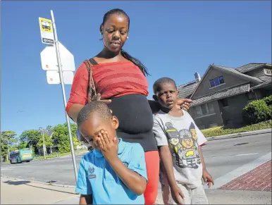  ??  ?? April Williams waits for the bus with two of her children, Solomon Blunt (left), 4, and Donovan Williams, 6, this month near their home on N. 39th St. Williams’ driver’s license was suspended last year for failure to pay tickets.