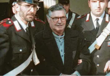  ?? Archivfoto: Gianni Schicchi, dpa ?? Bologna im Jahr 1996: Der italienisc­he Mafiaboss Salvatore „Totò“Riina (Mitte) wird in Handschell­en von Polizisten in den Gerichtssa­al geführt.