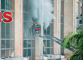  ??  ?? 消防員坐雲梯登高，擊破建築物玻璃，讓室內濃煙排出。（美聯社照片）