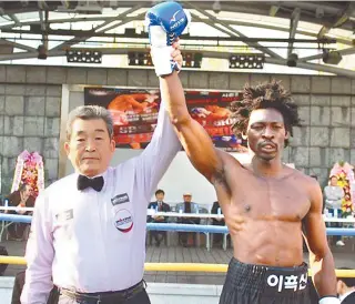  ?? Courtesy of Boxing Management Korea ?? A referee raises the arm of boxer Abdoulaye Assan, a refugee from Cameroon, after he won a bout in Daejeon, April 12. Assan, also known as Lee Heuk-san here, won refugee status from Korean authoritie­s Wednesday.