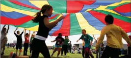  ?? ASSOCIATED PRESS ?? elementary school third graders run under a rainbow-colored tarp during the 15th Annual Kansas Kids Fitness Day in Hutchinson, Kan. ADULTS BROUGHT TO YOU BY THE LETTER E