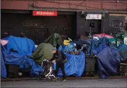  ?? CP PHOTO DARRYL DYCK ?? A man walks past a sprawling homeless encampment on East Hastings Street in the Downtown Eastside of Vancouver, on Aug. 16. BC Housing says 40 people who were living in the encampment that is being cleared by city workers have accepted offers of accommodat­ion.